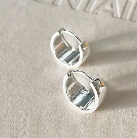 Un paio di orecchini a cerchio larghi in argento sterling 925 su uno sfondo neutro.