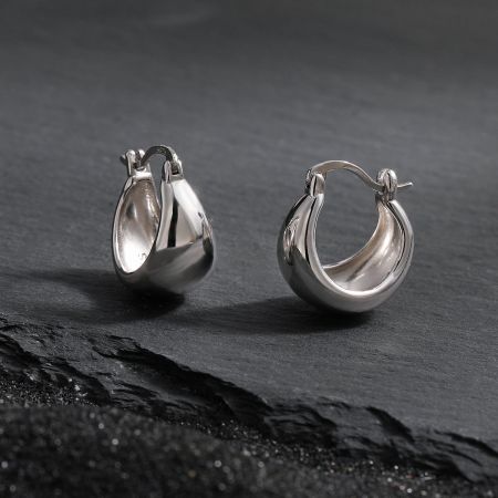 Närbild av de tjocka ringörhängena i 925 silver belagda med vitguld.