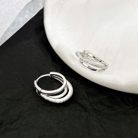 Due paia di orecchini a cerchio in argento sterling esposti, evidenziando la loro finitura brillante e le variazioni di design.