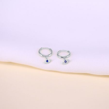 A pair of sterling silver hoop earrings showcasing the blue and clear gemstone evil eye charms.