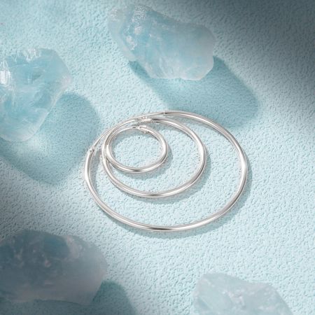 Un elegante disposizione degli orecchini a cerchio in argento con gemme blu decorative.