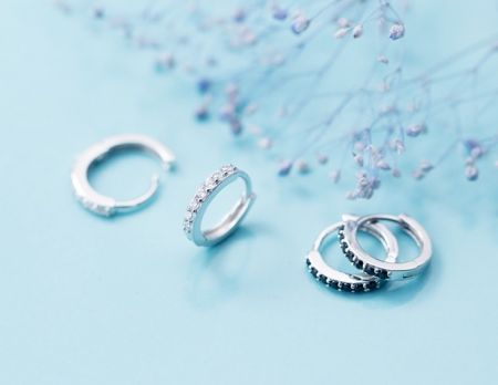 Una vetrina di orecchini a cerchio in argento che presentano sia pietre di zirconia cubica chiare che nere.