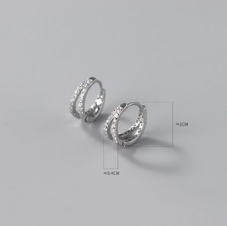 Vista dettagliata di un orecchino a cerchio in argento con accenti di zirconia cubica scintillante e guide di misurazione.