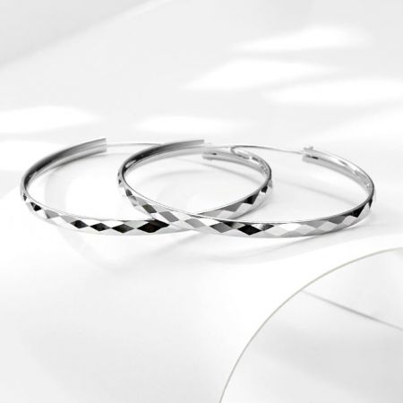 Un altro angolo degli orecchini a cerchio in argento da 42 mm, enfatizzando la loro superficie sfaccettata e riflettente.