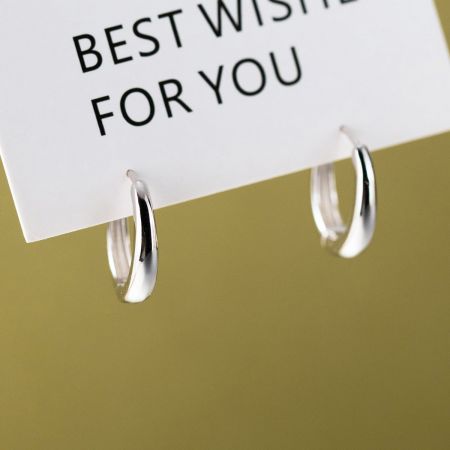 Gli orecchini a cerchio in argento minimalista presentati con un elegante biglietto d'auguri, rendendoli un'opzione regalo ideale.