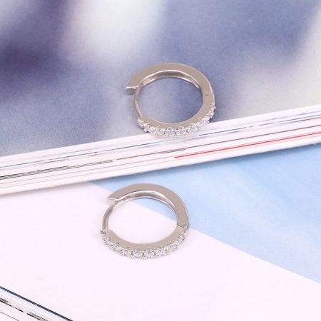 Orecchini a cerchio piccoli in zirconia micro-inserita in argento sterling 925 - Primo piano di un paio di orecchini a cerchio in argento sterling 925, elegantemente dettagliati con pietre di zirconia micro-inserite, su uno sfondo neutro.