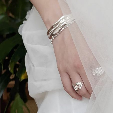 La mano de un modelo mostrando múltiples anillos del conjunto de anillos ajustables de perla de concha de estilo francés.