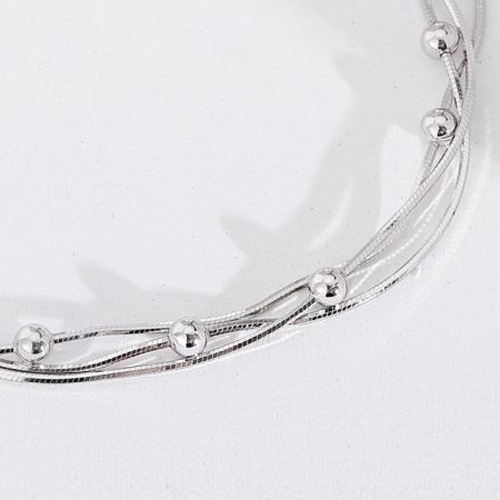 Artistic shot of the interwoven wires and decorative beads on the silver bracelet.