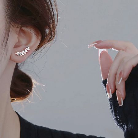 Close-up van een vrouw die de zilveren bladstud oorbel draagt om de schaal en het uiterlijk te tonen.