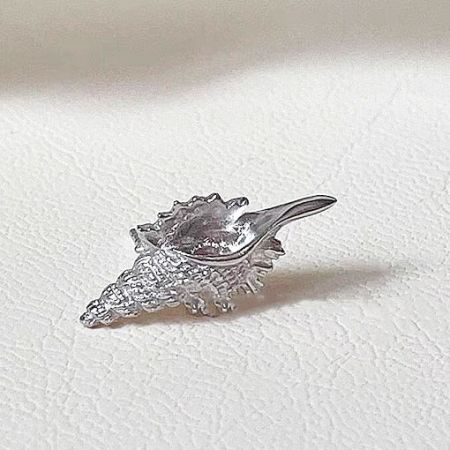 Detailed close-up of a silver conch shell stud earring.