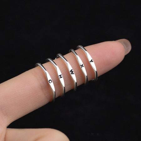 Bagues Ajustables de l'Alphabet de 26 Lettres en Argent Sterling 925 - Un ensemble de cinq bagues ajustables en argent sterling 925, chacune portant une lettre de l'alphabet gravée différente, présentées sur un fond blanc propre.