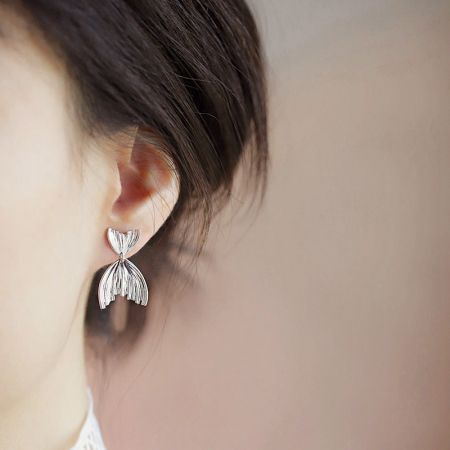 Ein Modell trägt die Ohrringe in Form eines Meerjungfrauen-Schwanzes aus Sterlingsilber, um deren Maßstab und Stil zu zeigen.