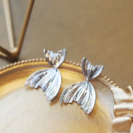 Orecchini pendenti a forma di coda di sirena in argento sterling 925 (5 paia) - Un paio di orecchini pendenti a forma di coda di sirena in argento sterling 925 elegantemente esposti su un piatto dorato, mostrando il loro design intricato.