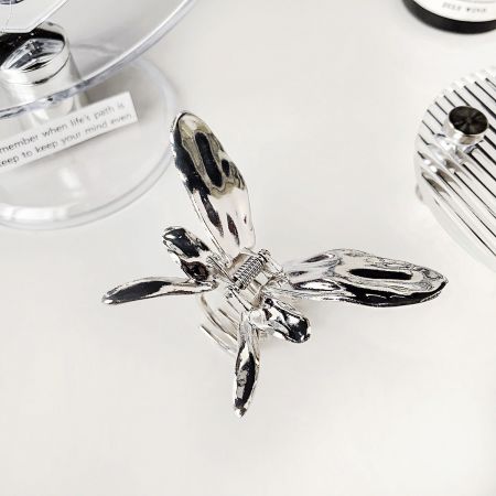 Clips para el cabello en forma de mariposa de moda de metal. - Un primer plano detallado de un clip para el cabello en forma de mariposa de metal plateado brillante, mostrando su intrincado diseño de alas y construcción duradera.