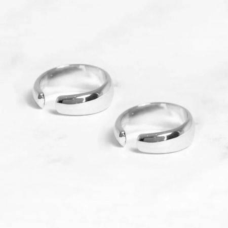 Coppia di bracciali auricolari a forma di C in argento su uno sfondo bianco.