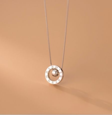 Detailed view of the silver necklace pendant, featuring a unique clock-face design with a rotating center.