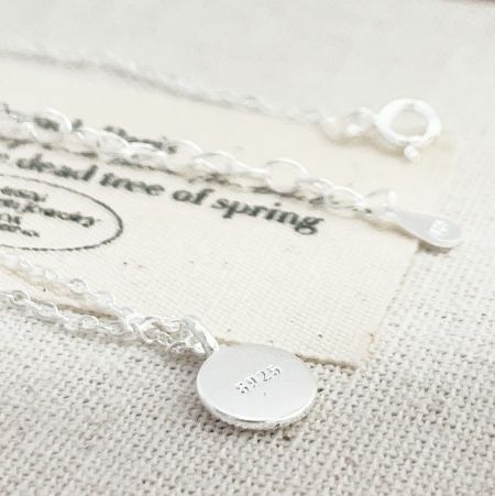Gros plan de l'arrière du pendentif en argent, montrant les détails gravés.
