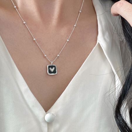 Modèle portant le collier pendentif en argent sterling avec un cœur noir pour mettre en valeur sa longueur et son style.