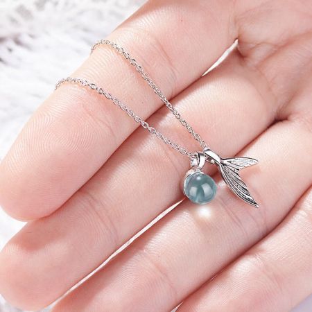 Vista laterale di una collana in argento con un pendente unico che presenta una perla blu-grigia e un ciondolo a forma di ala.