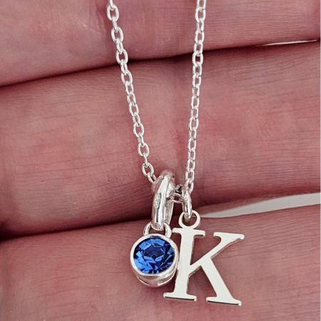 Gepersonaliseerde Alfabet Letter Ketting met Geboortesteen Accent - Een close-up van de gepersonaliseerde alfabet letter ketting, met een 'K' initialen hanger in 14K verguld roestvrijstaal met een levendige blauwe geboortesteen accent.