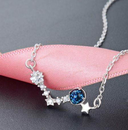 Collar de estrellas de deseo de plata esterlina 925 - Una toma de estudio detallada del collar de estrellas de deseo de plata esterlina 925, destacando su gema azul central y los delicados encantos de circonita cúbica en forma de estrella en una cadena de plata.
