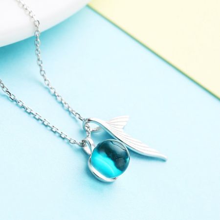Collana in argento sterling che mostra un pendente distintivo con una perla di cristallo blu-verde e design a forma di ala.