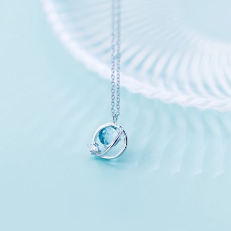 Detailed view of the sterling silver planet pendant with its intricate design and blue stone.