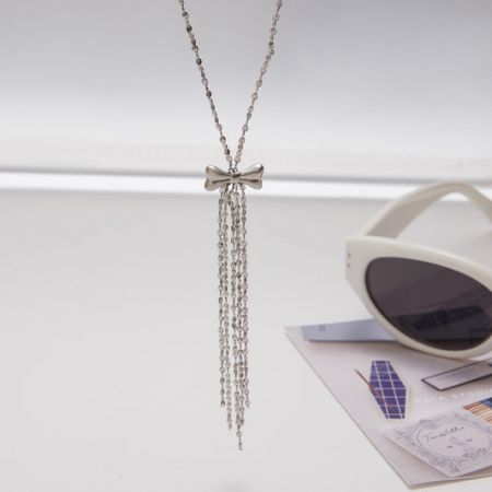 A stylish stainless steel necklace featuring a bow and tassel pendant.