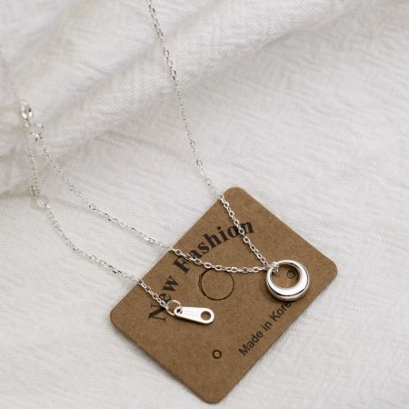 Detailed view of the silver circle pendant necklace on its display card.
