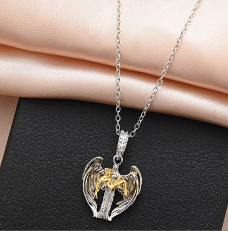 Gros plan sur un collier en argent personnalisé avec un pendentif d'ange aux ailes dorées.