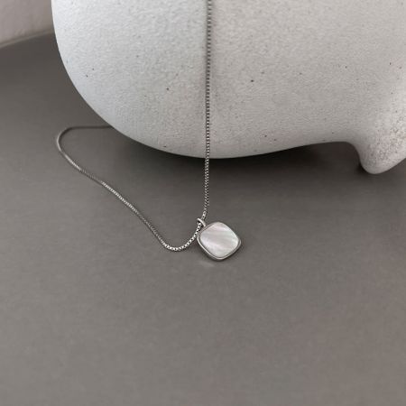 El collar con colgante de concha cuadrada en un acabado clásico de plata esterlina, mostrando su calidad iridiscente.