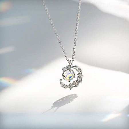 A 925 silver necklace from the set, featuring a pendant with an iridescent stone and a delicate bird in flight design.