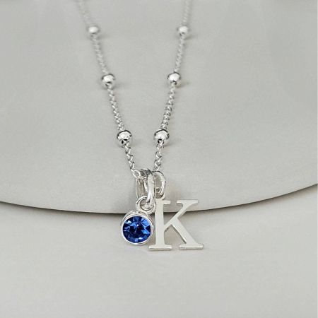 Detailed shot of the gold-plated 'K' pendant and birthstone on the stainless steel chain.