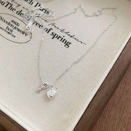 Le collier avec pendentif cœur et clé en argent sterling présenté clairement pour montrer son artisanat.