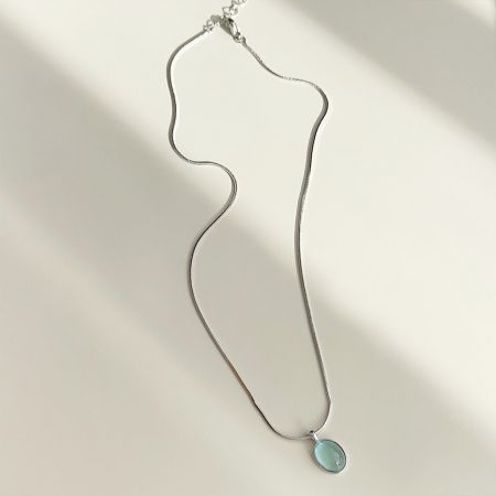 A unique silver necklace with a distinctive wavy chain and a light blue pendant.