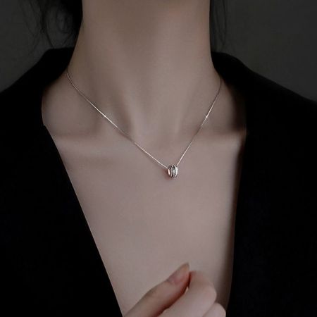 Product shot of a silver necklace from the set with a delicate oval pendant on a white background.