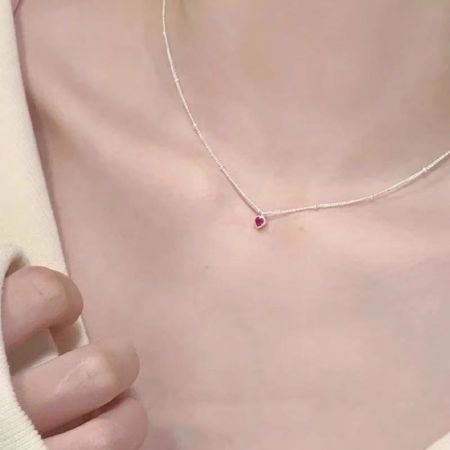 Detailed view of the small red zircon heart pendant on the silver chain.