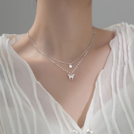 Model showcasing the layered silver butterfly and star pendant necklaces.