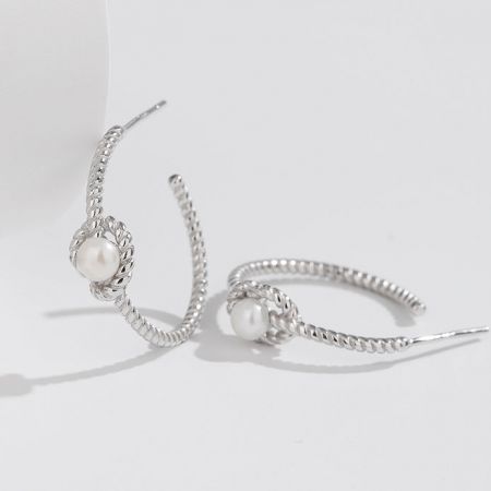Scatto dettagliato degli orecchini in argento che mostrano gli accenti di perla lucente.