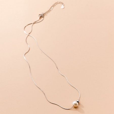 Another product view of the silver necklace with its pearl pendant against a white background.