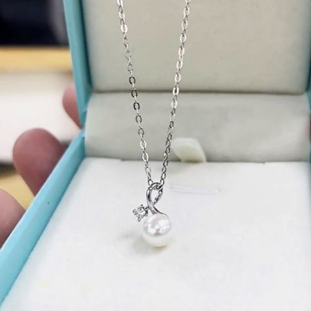 The elegant pearl and cubic zirconia necklace presented in a stylish light blue jewelry box, perfect for gifting.
