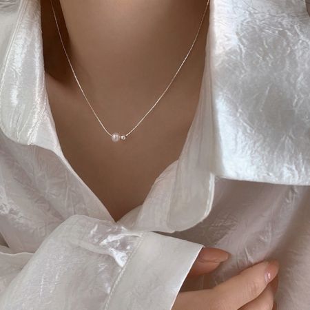 Modelo usando el collar de dos perlas de plata esterlina, mostrando su ajuste elegante.
