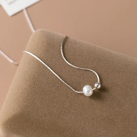 Primer plano de un collar de plata esterlina 925 con un gran colgante de perla blanca lustrosa.