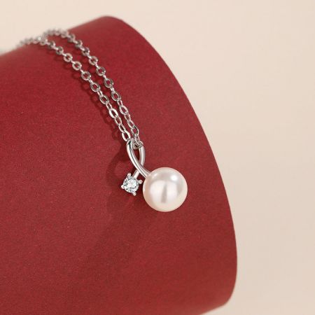 Collar con colgante de perla y circonitas de plata esterlina 925 - Un primer plano de un collar de plata esterlina 925 con un clásico colgante de perla blanca acentuado con un brillante charm de circonita.