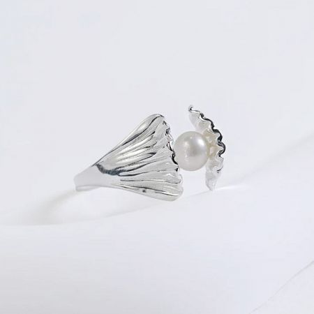 Un anillo de plata esterlina con un diseño de concha que sostiene una perla, del conjunto ajustable de cinco.