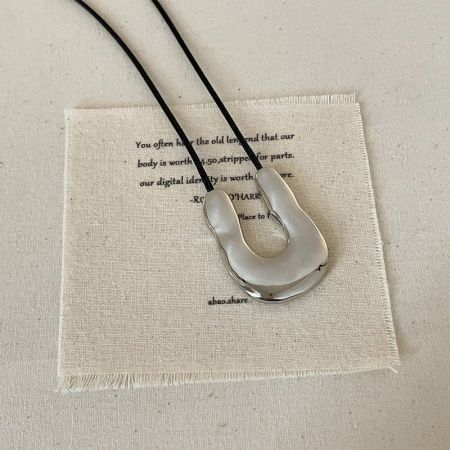 Close-up of the silver U-shape pendant on a black cord, highlighting its sleek minimalist design.