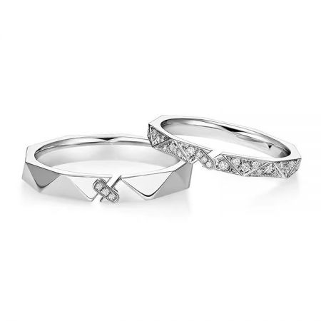 Die Ringe des Paares nebeneinander, einer schlicht und einer mit diamantähnlichen Steinen, die das puzzleartige Design veranschaulicht.