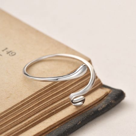 Toma detallada del acabado pulido y las puntas curvadas del anillo de serpiente de plata minimalista.