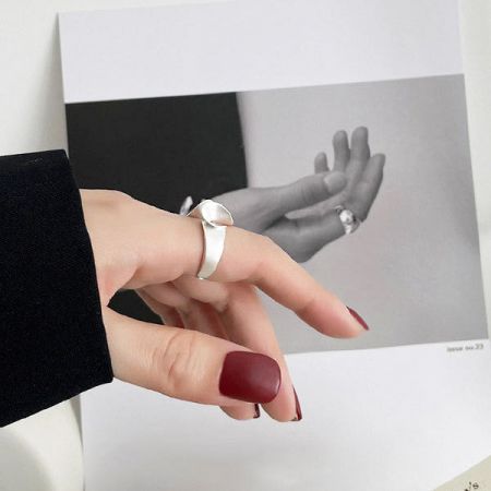 Imagen de estilo de vida del anillo de plata esterlina en una mano con uñas rojas, destacando su atractivo de moda.