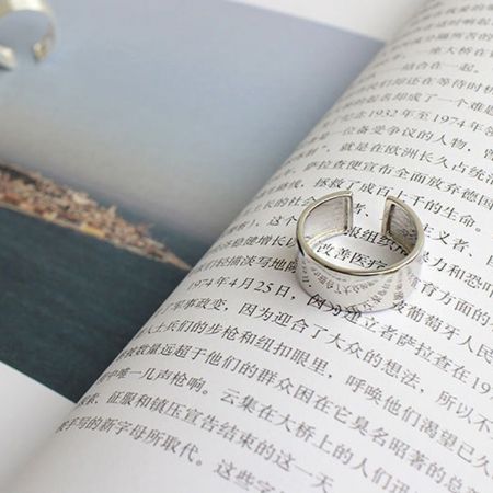 Une seule bague en argent sterling de 9 mm de large reposant sur un livre, mettant en avant son design minimaliste et élégant.